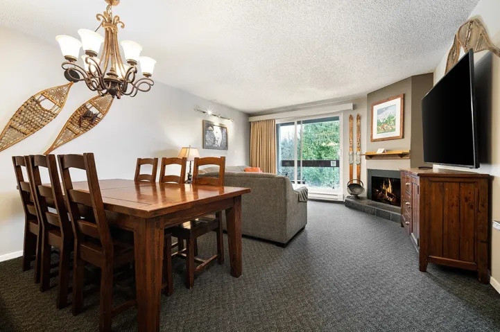 Dining room featuring dark colored carpet, a textured ceiling, a lit fireplace, and hanging lights