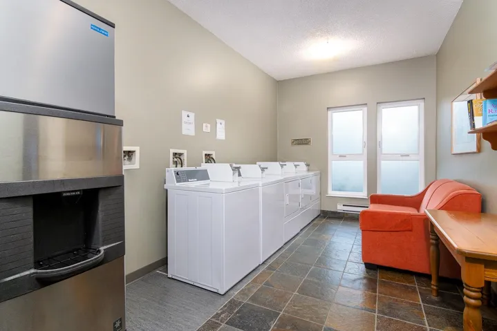 Communal laundry room with a textured ceiling, baseboard heating, and washing machine and dryer