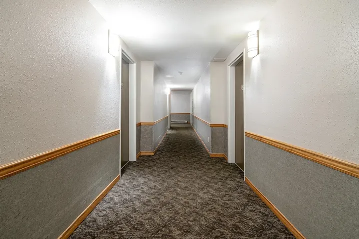 Hall featuring a textured wall and dark carpet