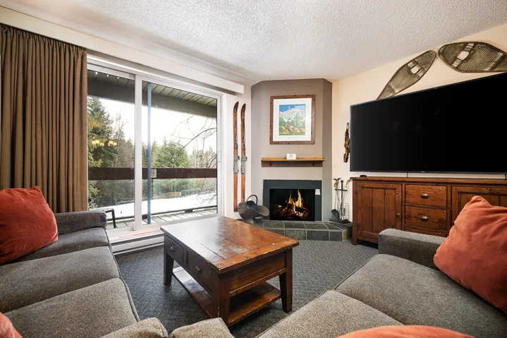 Carpeted living area featuring a tile fireplace, a textured ceiling, and a baseboard radiator
