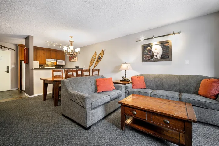 Living room featuring suspended lighting, a textured ceiling, and dark carpet