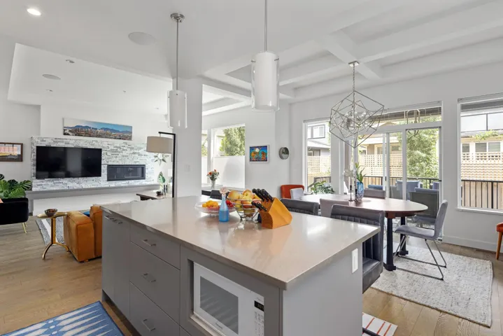 Kitchen featuring light wood-style floors, white microwave, gray cabinetry, beam ceiling, and coffered ceiling