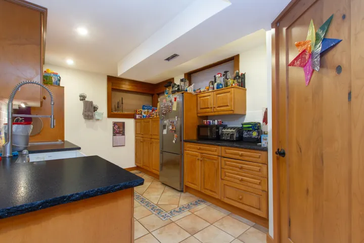 Kitchen featuring light tile patterned floors, dark countertops, freestanding refrigerator, and recessed lighting