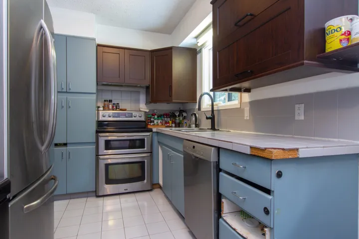 Kitchen featuring light tile patterned floors, tasteful backsplash, tile countertops, stainless steel appliances, and a sink