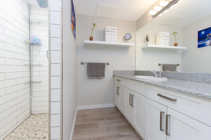 Bathroom with vanity, wood finished floors, baseboards, and tiled shower