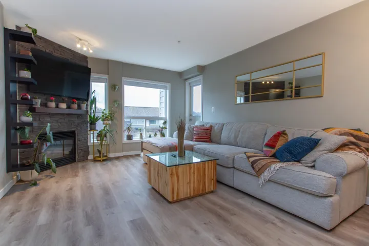 Living area featuring a stone fireplace, baseboards, and light wood-style floors