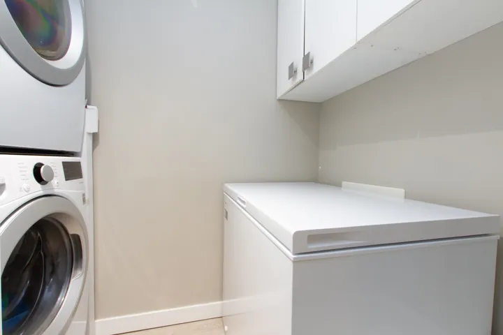 Washroom featuring cabinet space and stacked washer / drying machine