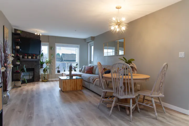 Dining area featuring light wood-style flooring, baseboards, a large fireplace, and an inviting chandelier