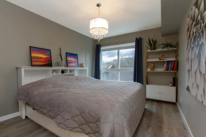 Bedroom with wood finished floors, baseboards, and a chandelier