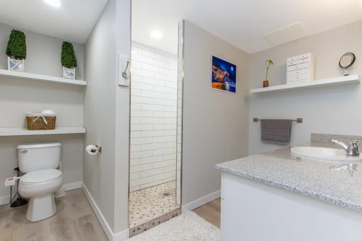 Full bath with baseboards, toilet, tiled shower, wood finished floors, and vanity
