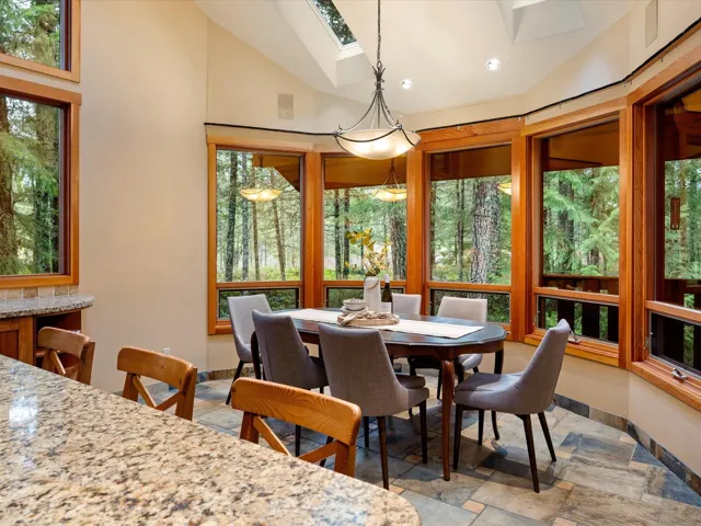 Dining area with a skylight, healthy amount of natural light, stone tile flooring, and high vaulted ceiling