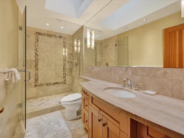 Bathroom with vanity, a shower stall, tile walls, decorative backsplash, and light tile patterned floors