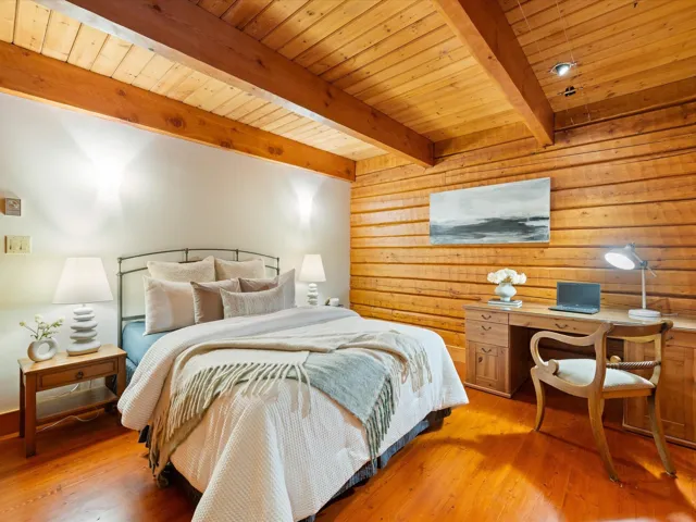Bedroom featuring wood walls, light wood finished floors, wooden ceiling, and a desk
