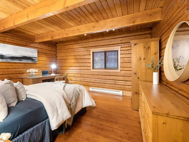 Bedroom featuring wood walls, hardwood / wood-style flooring, a baseboard heating unit, and a wooden ceiling with exposed beams