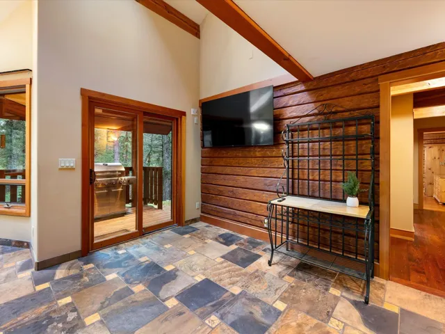 Sitting room with rustic walls, stone tile flooring, high vaulted ceiling, and beamed ceiling