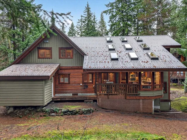 Back of house with a metal roof, a deck, and board and batten siding