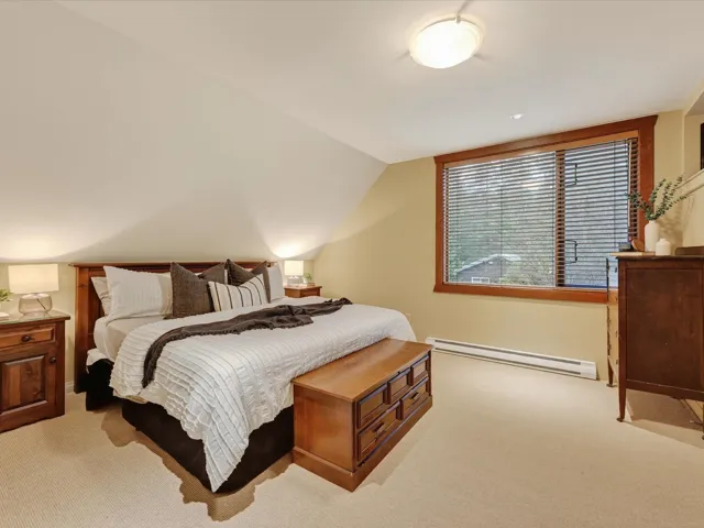 Bedroom featuring a baseboard heating unit, vaulted ceiling, and light colored carpet