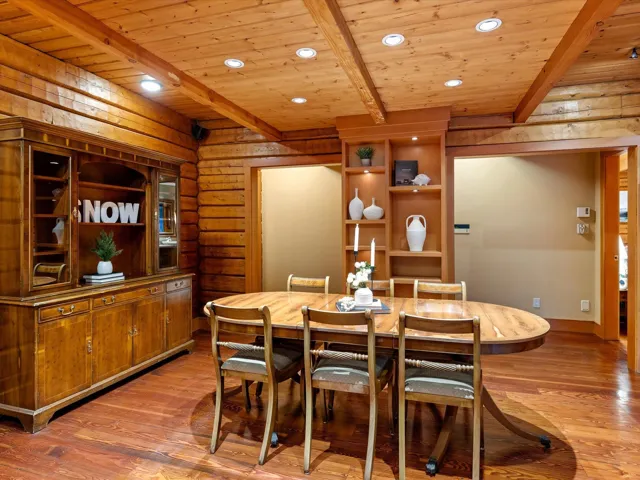 Dining space featuring light wood finished floors, a wooden ceiling with exposed beams, built in shelves, rustic walls, and recessed lighting