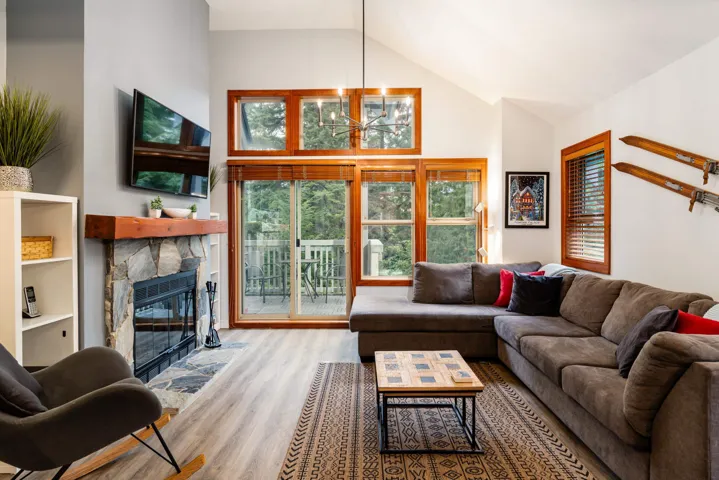 Living area featuring a fireplace, plenty of natural light, wood finished floors, high vaulted ceiling, and a chandelier