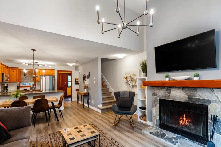 Living room featuring a chandelier, light wood-style flooring, stairway, a towering ceiling, and a fireplace