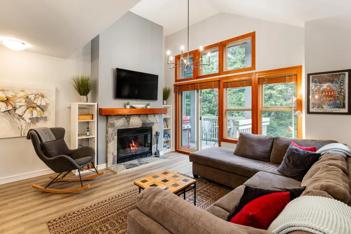 Living room with high vaulted ceiling, a fireplace, wood finished floors, and a chandelier