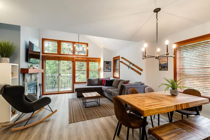 Dining area featuring a chandelier, light wood finished floors, a stone fireplace, and vaulted ceiling