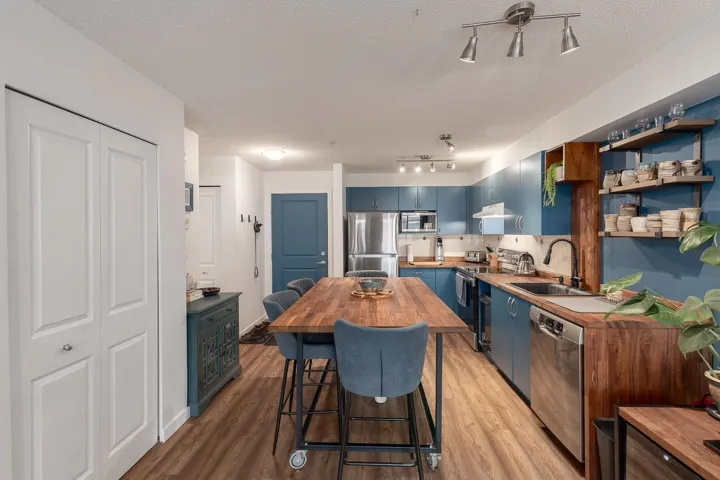 Kitchen featuring blue cabinetry, stainless steel appliances, a textured ceiling, light wood finished floors, and tasteful backsplash