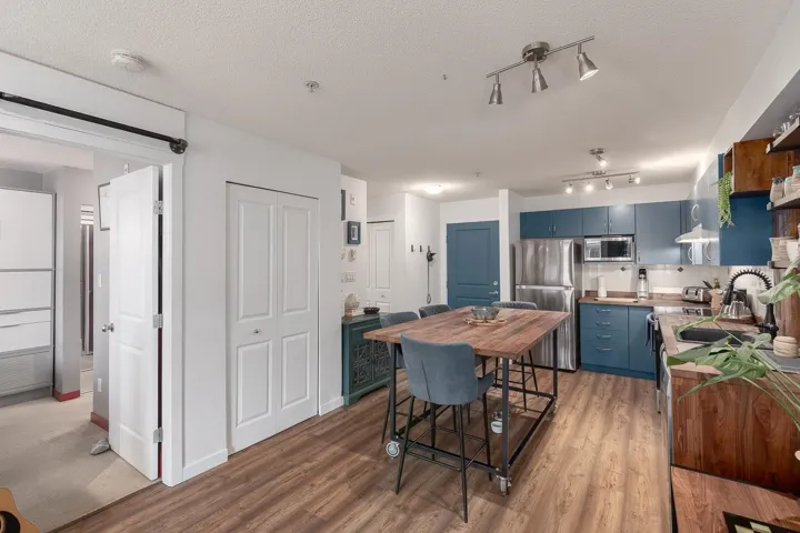 Kitchen featuring blue cabinetry, stainless steel appliances, light countertops, open shelves, and light wood-style floors