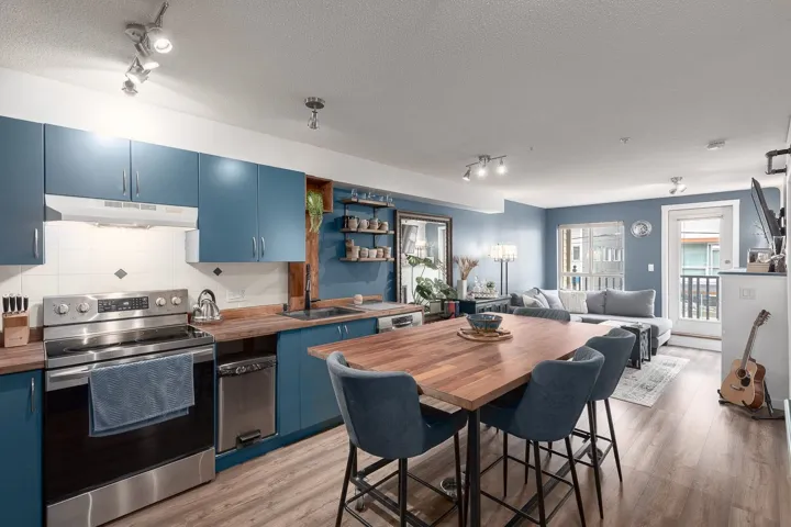 Kitchen featuring blue cabinets, electric range, track lighting, light wood-type flooring, and a textured ceiling