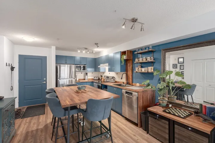 Kitchen featuring blue cabinetry, stainless steel appliances, light wood finished floors, a textured ceiling, and butcher block countertops