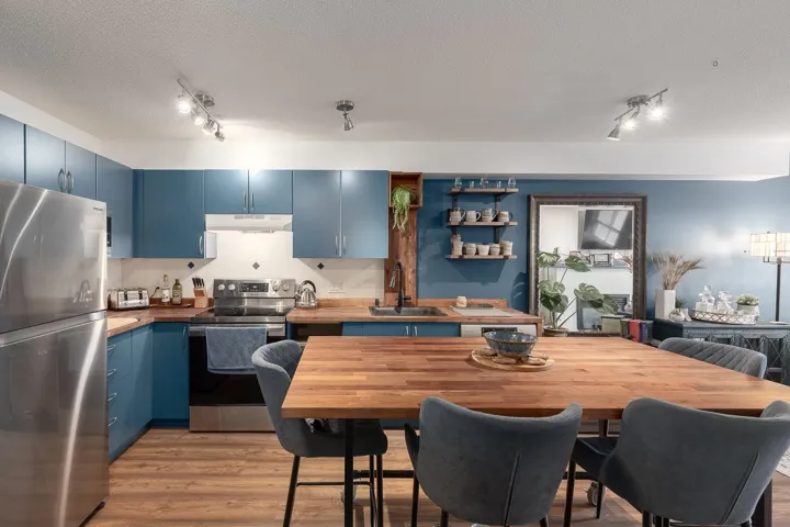 Kitchen featuring blue cabinetry, stainless steel appliances, track lighting, decorative backsplash, and light wood finished floors