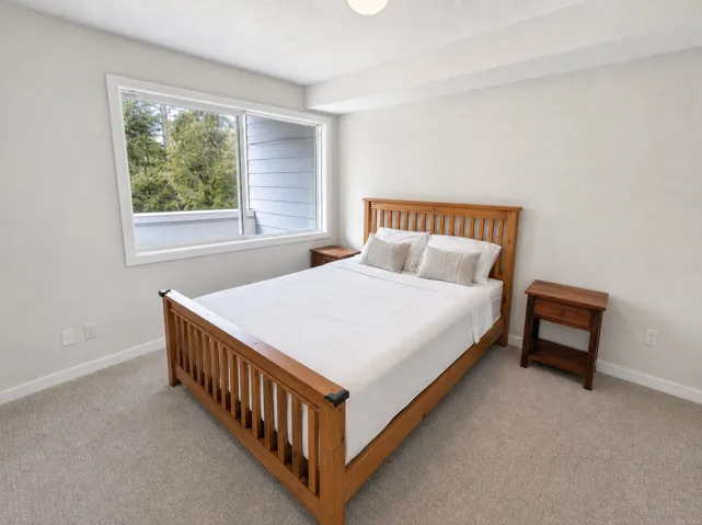 Bright interior with neutral wall colors, expansive window, and carpeting