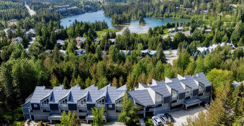 Contemporary multi-unit property featuring a striking roofline and an abundance of surrounding mature trees