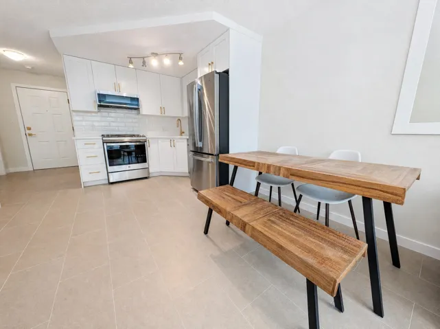Modern kitchen featuring white cabinetry with brushed nickel hardware, stainless steel French-door refrigerator, and built-in wall oven with microwave