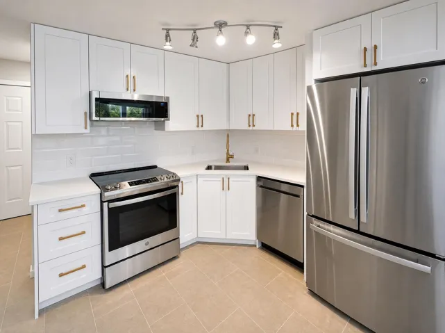 Contemporary kitchen featuring white cabinetry, stainless steel appliances, a white subway tile backsplash, light-toned tile flooring, and track lighting