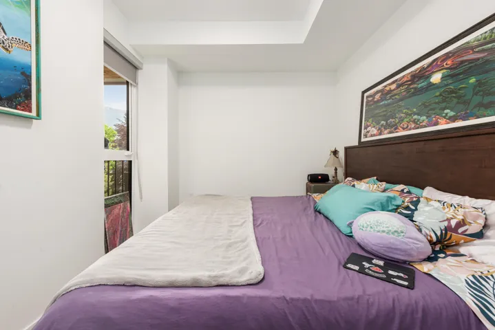 Bedroom featuring a large window, recessed ceiling detail, and a dark wood-finish headboard