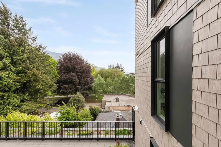 Spacious outdoor patio with black metal railing, offering expansive tree-lined surroundings