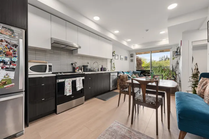 Contemporary kitchen featuring stainless steel appliances, dark wood-finish base cabinetry, light upper cabinetry, and a light tile backsplash