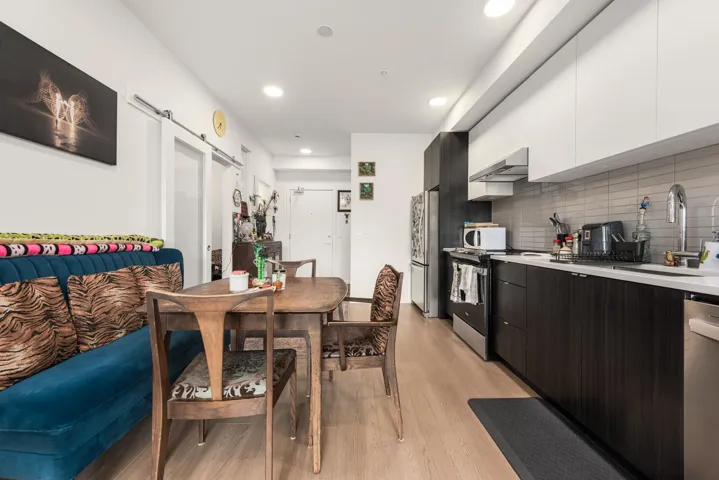 Modern kitchen featuring white upper cabinetry, dark wood-finish lower cabinetry, white countertops, and a subway tile backsplash