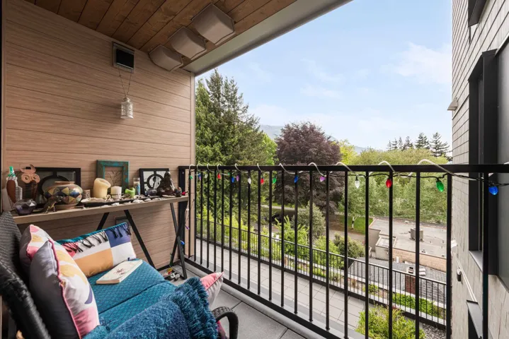Private balcony featuring a wood-panel accent wall, wood-finish ceiling, and black metal railing