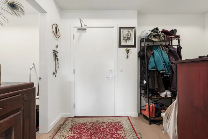 Entryway featuring light wood-finish flooring, white walls, and a solid white entrance door with a door closer