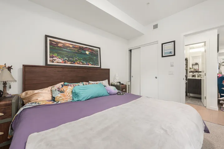 Bedroom featuring a wood-finish headboard, bright white walls, and a recessed ceiling beam