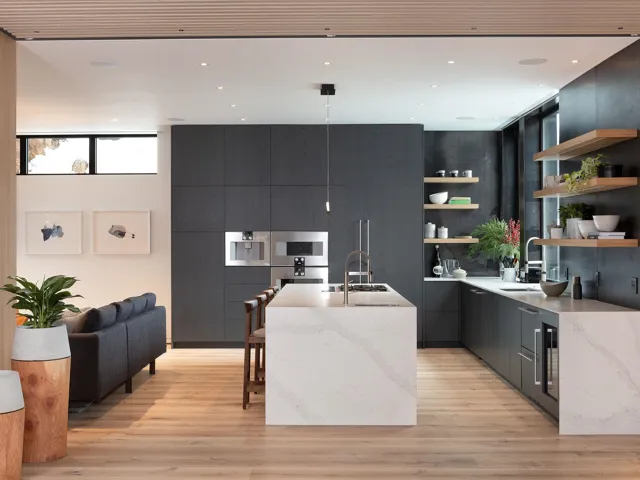 Kitchen with open shelves, light stone counters, a kitchen island with sink, modern cabinets, and a kitchen breakfast bar