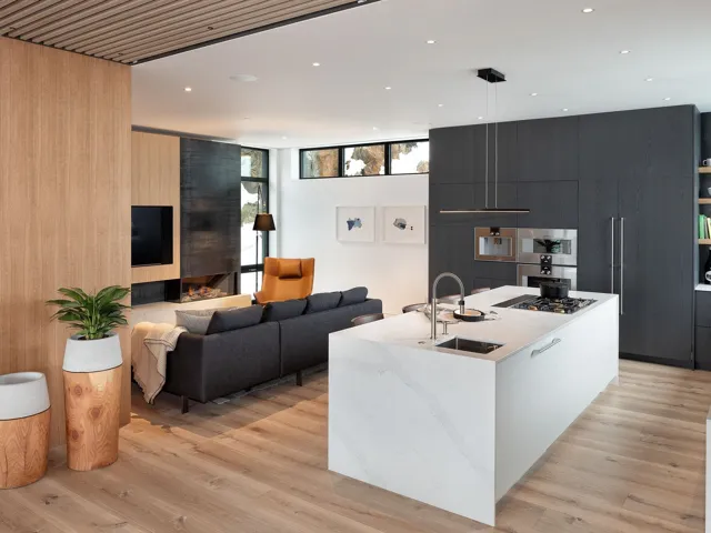 Kitchen featuring modern cabinets, open floor plan, an island with sink, light wood-style flooring, and wood walls