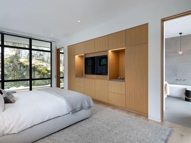 Bedroom featuring light wood finished floors, expansive windows, recessed lighting, and connected bathroom