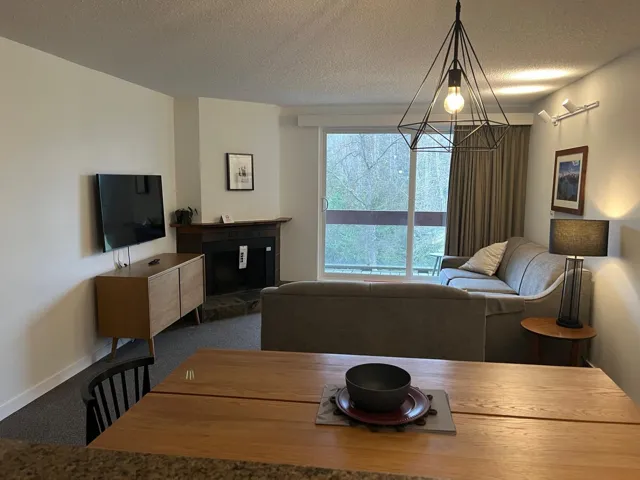 Dining area with a textured ceiling, carpet flooring, a glass covered fireplace, and a chandelier