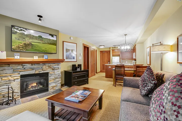 Living area featuring light colored carpet, a notable chandelier, and a stone fireplace