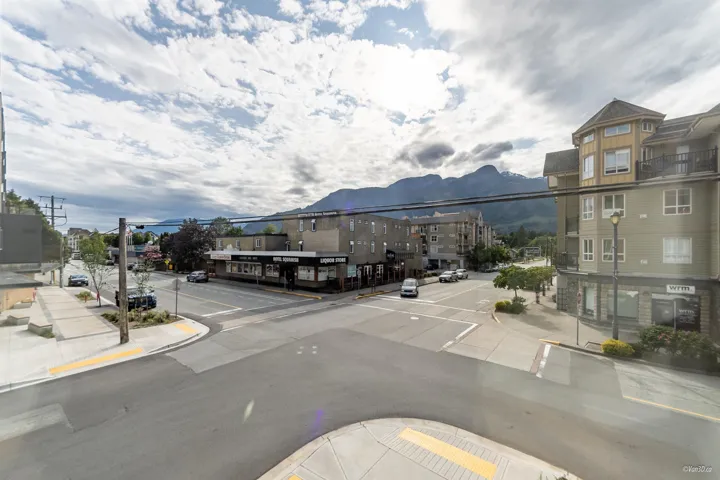 View of asphalt street featuring sidewalks, curbs, street lighting, and a mountain view
