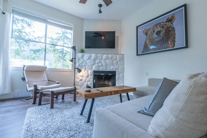 Living room with wood finished floors, a ceiling fan, and a fireplace