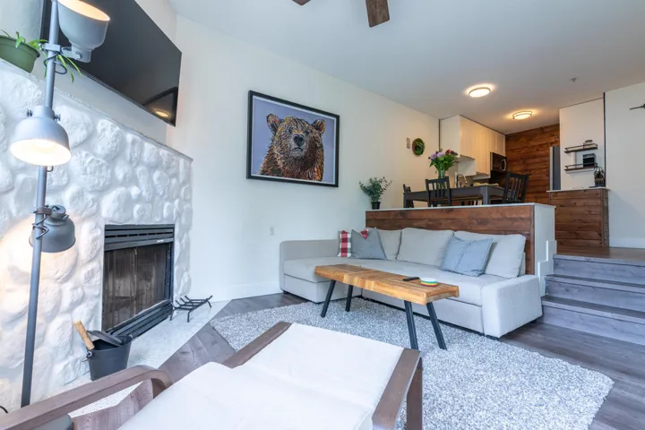 Living area with a fireplace, wood finished floors, baseboards, and ceiling fan